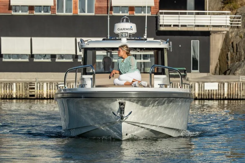 Slide: The Image of 2024 Nimbus C9 boat with a person seated on the bow, near a modern building. - 17