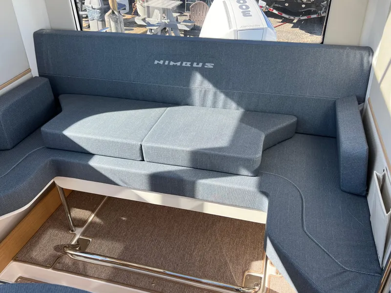 Slide: The Image of 2024 Nimbus C9 boat interior with blue cushioned seating and table. - 8