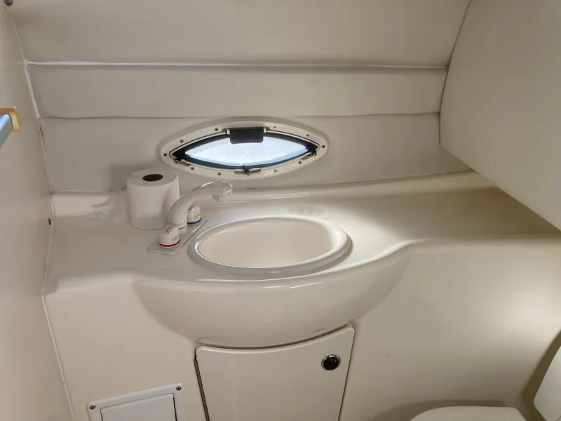 Slide: The Image of 2004 Bayliner 245 Cruiser bathroom with sink, faucet, and oval window. - 22