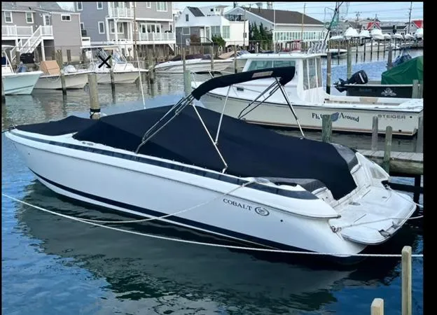 The Image of 2006 Cobalt 262 boat docked in a marina, covered with a black tarp. - 0