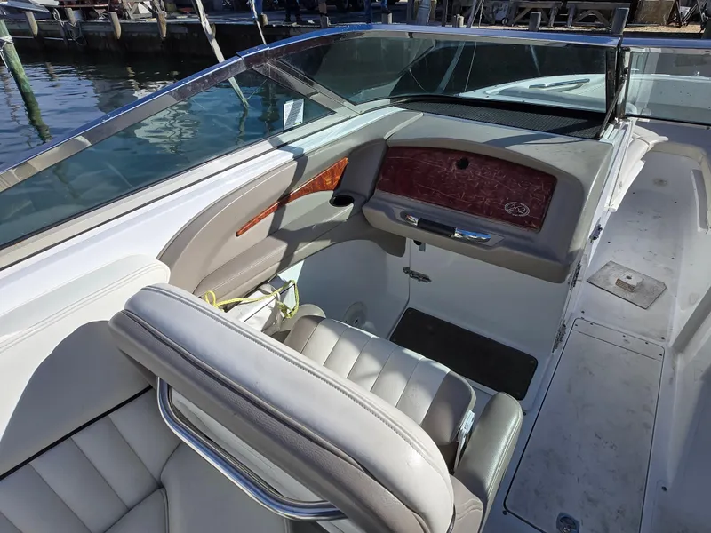 Slide: The Image of 2006 Cobalt 262 boat interior with leather seating and wood accents, docked by the water. - 11
