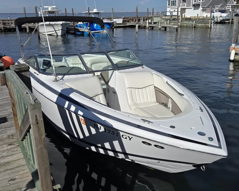Slide: The Image of 2006 Cobalt 262 boat docked at a marina, featuring sleek white design and spacious seating. - 2