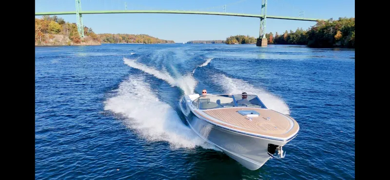 Slide: The Image of 2024 Comitti Venezia V28 speedboat cruising under a bridge on a sunny day. - 0