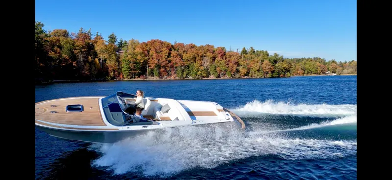 Slide: The Image of 2024 Comitti Venezia V28 speedboat cruising on a lake with autumn foliage backdrop. - 1