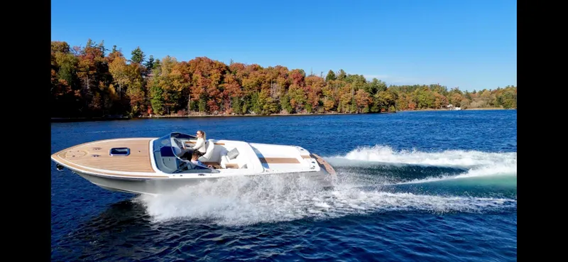Slide: The Image of 2024 Comitti Venezia V28 speedboat cruising on a lake with autumn foliage backdrop. - 13