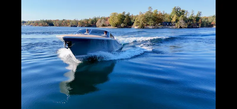 Slide: The Image of 2024 Comitti Venezia V28 cruising on a serene lake with lush trees in the background. - 2