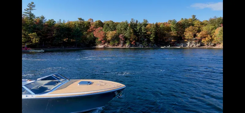 Slide: The Image of 2024 Comitti Venezia V28 boat cruising on a scenic lake with autumn foliage. - 24