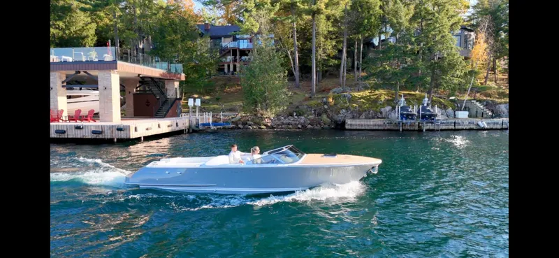 Slide: The Image of 2024 Comitti Venezia V28 cruising on a scenic lake near a dock and forested shoreline. - 28