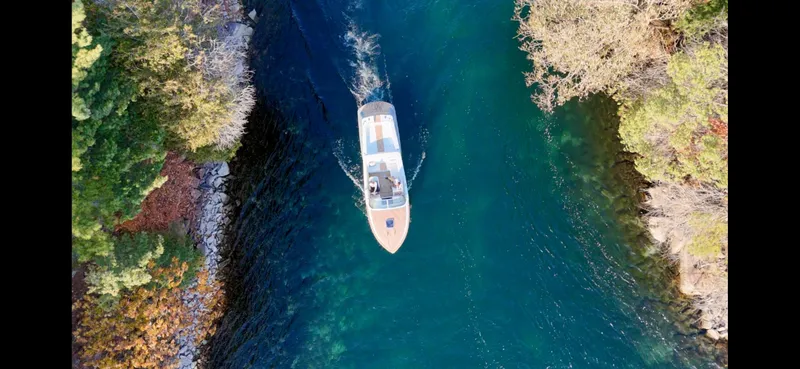 Slide: The Image of Aerial view of 2024 Comitti Venezia V28 boat navigating through a narrow, tree-lined waterway. - 30