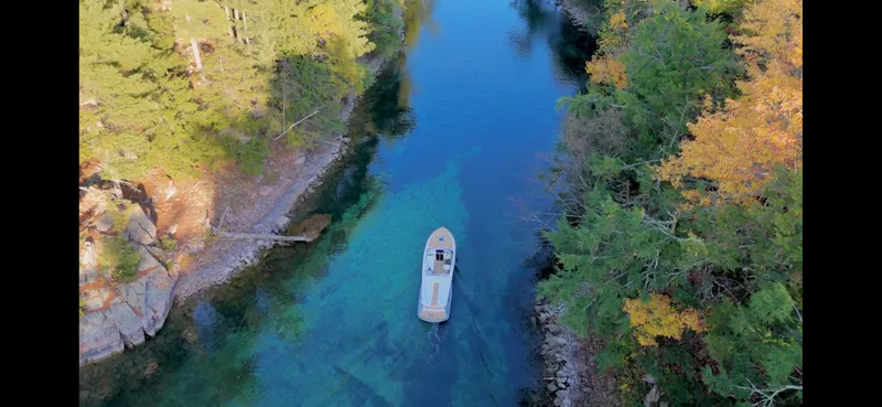 Slide: The Image of Aerial view of 2024 Comitti Venezia V28 boat on a clear, forest-lined river. - 32