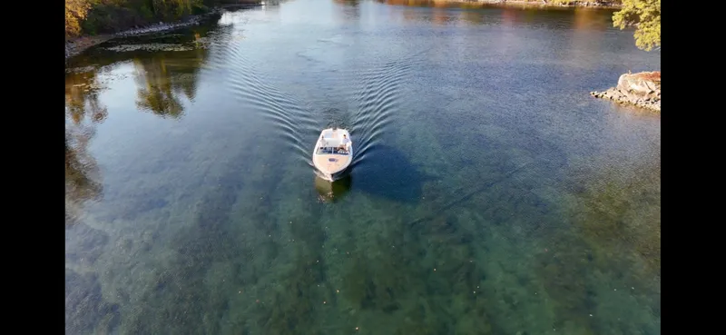 Slide: The Image of 2024 Comitti Venezia V28 cruising on a serene, clear waterway surrounded by lush greenery. - 33