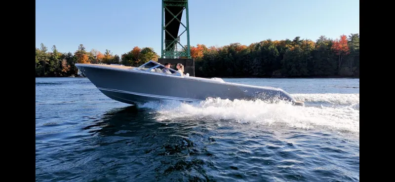 Slide: The Image of 2024 Comitti Venezia V28 speedboat cruising on a lake under a bridge, surrounded by autumn trees. - 6