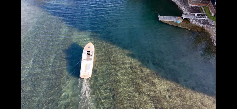 Slide: The Image of Aerial view of 2024 Comitti Venezia V28 boat cruising in clear waters near a shoreline. - 7