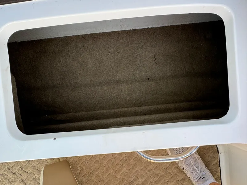 Slide: The Image of Open storage compartment in a 2015 Cobalt 220 boat, with visible carpeted interior. - 14