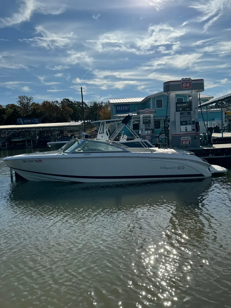Slide: The Image of 2015 Cobalt 220 boat docked at a marina with gas pumps under a sunny sky. - 4