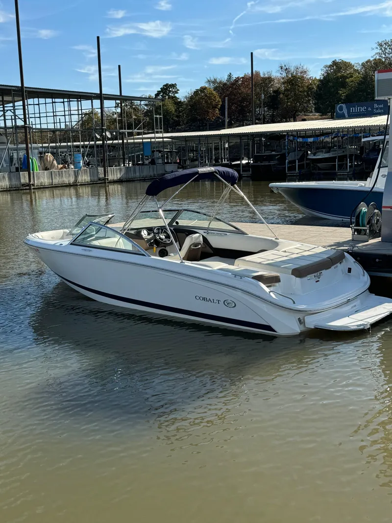 Slide: The Image of 2015 Cobalt 220 boat docked in a marina, calm water, clear sky. - 5
