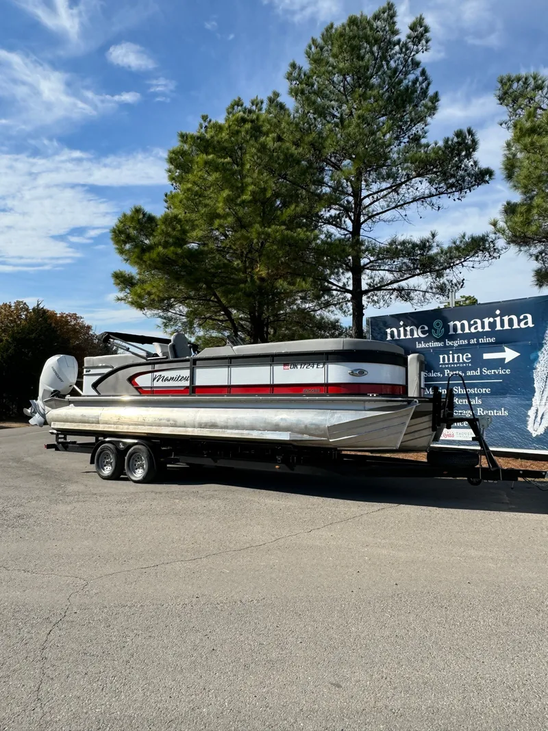 The Image of 2022 Manitou Encore 250SHP pontoon boat on trailer at marina. - 1