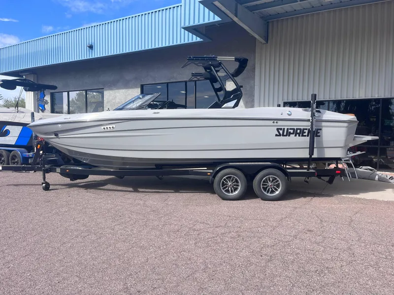 Slide: The Image of 2025 Supreme S240 boat on trailer outside a building. - 1