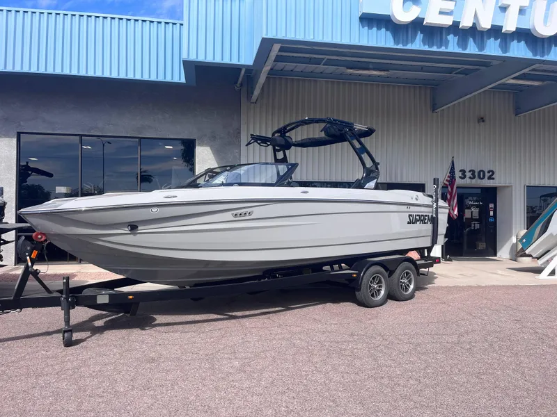 Slide: The Image of 2025 Supreme S240 boat on trailer outside dealership. - 2