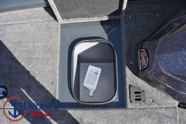 Slide: The Image of Ranger RT198P 2025 boat storage compartment with bottle, carpeted interior, and logo detail. - 16