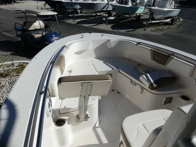 Slide: The Image of 2023 Robalo R200 boat interior with seating and storage, parked near golf cart. - 16