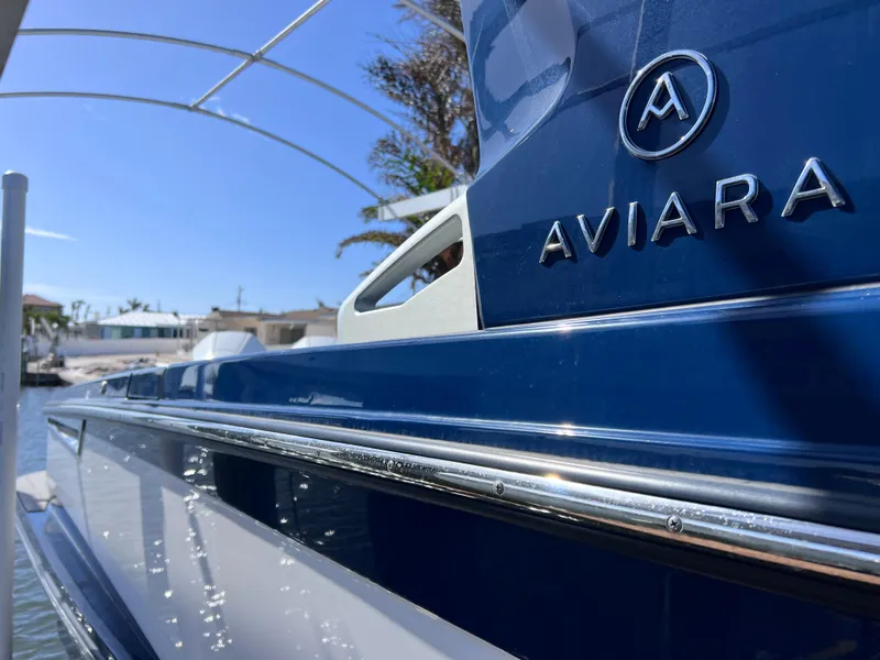 Slide: The Image of Close-up of 2022 Aviara AV 32 Outboard boat, showcasing sleek blue design and logo. - 17