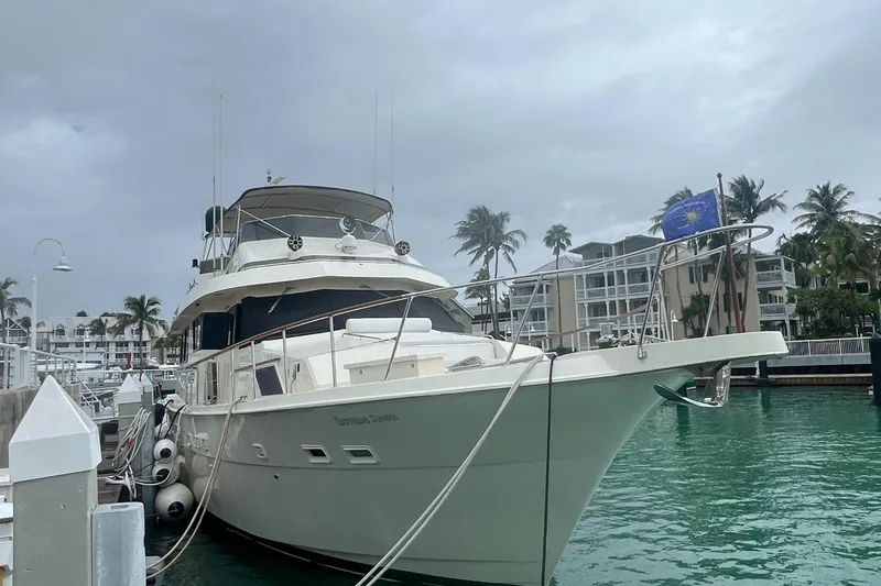 Slide: The Image of 1990 Hatteras 70 Cockpit Motor Yacht docked in a marina with palm trees. - 10