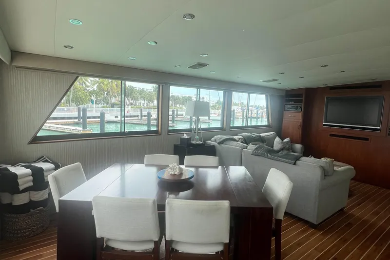 Slide: The Image of Interior of 1990 Hatteras 70 Cockpit Motor Yacht with dining area and large windows. - 13