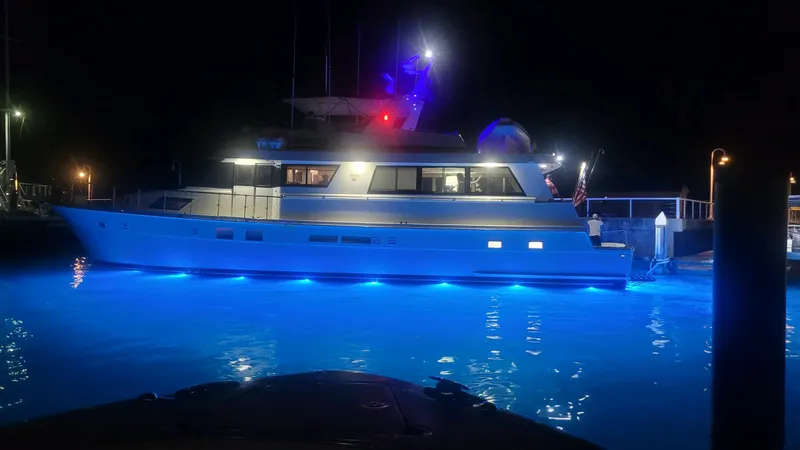 Slide: The Image of 1990 Hatteras 70 Cockpit Motor Yacht illuminated at night with blue underwater lights. - 2