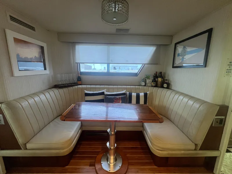 Slide: The Image of Interior of 1990 Hatteras 70 Cockpit Motor Yacht with cozy dining area and wooden table. - 27
