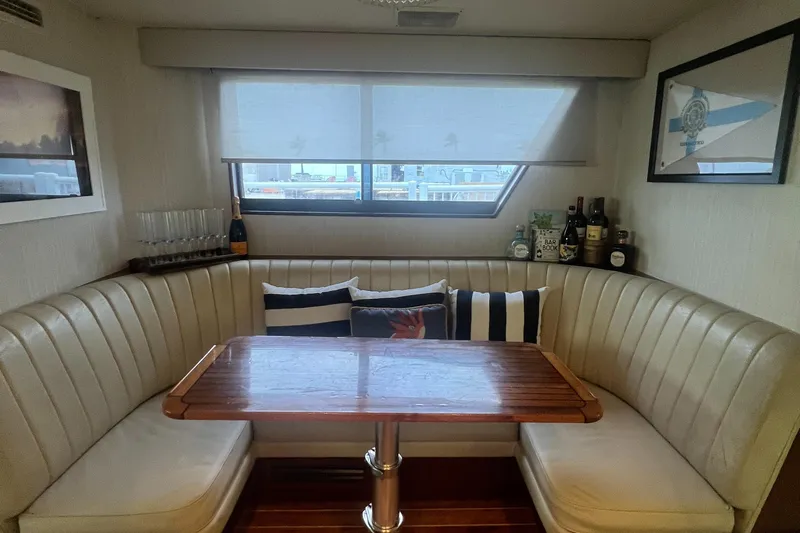 Slide: The Image of Cozy dining nook in 1990 Hatteras 70 Cockpit Motor Yacht with plush seating and wooden table. - 28