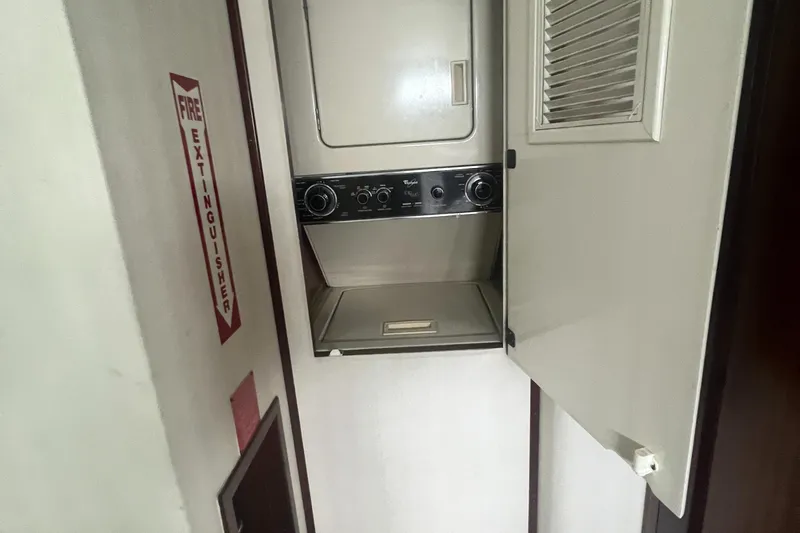 Slide: The Image of 1990 Hatteras 70 Cockpit Motor Yacht laundry area with stacked washer and dryer. - 31