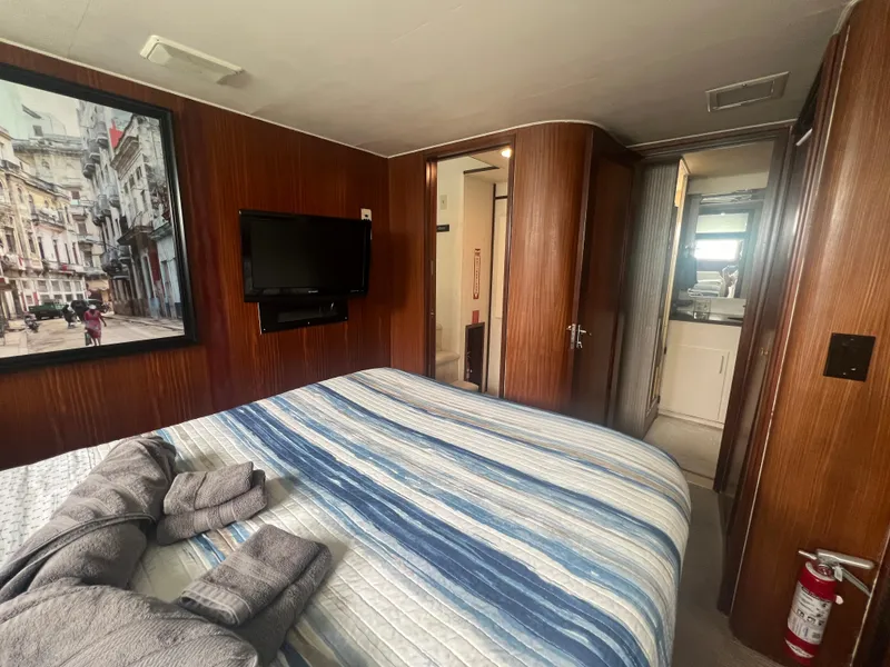 Slide: The Image of Interior of 1990 Hatteras 70 Cockpit Motor Yacht bedroom with TV and striped bedding. - 33