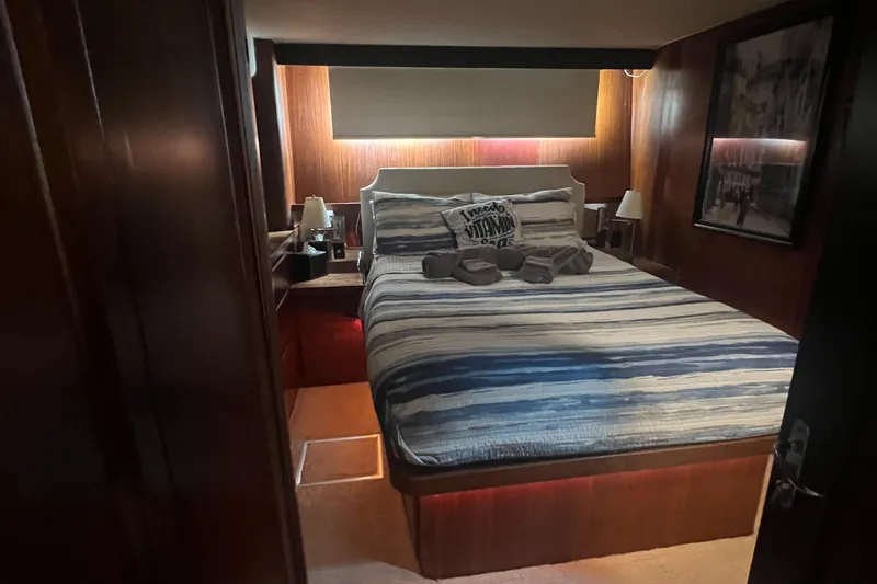 Slide: The Image of Luxurious bedroom in 1990 Hatteras 70 Cockpit Motor Yacht with striped bedding and warm lighting. - 36