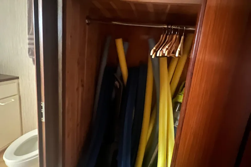 Slide: The Image of Closet with pool noodles and hangers on a 1990 Hatteras 70 Cockpit Motor Yacht. - 40