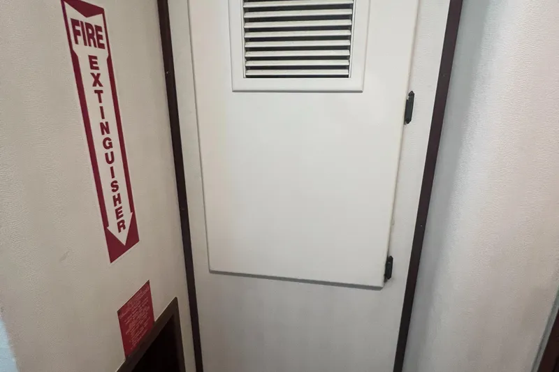 Slide: The Image of Fire extinguisher sign and vented door on 1990 Hatteras 70 Cockpit Motor Yacht. - 44