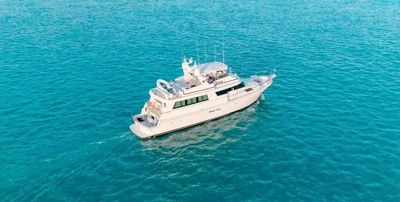 Slide: The Image of 1990 Hatteras 70 Cockpit Motor Yacht cruising on clear blue water. - 5