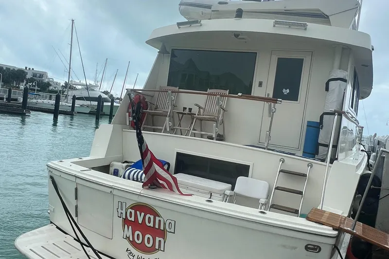 Slide: The Image of 1990 Hatteras 70 Cockpit Motor Yacht docked, featuring "Havana Moon" name on stern. - 9