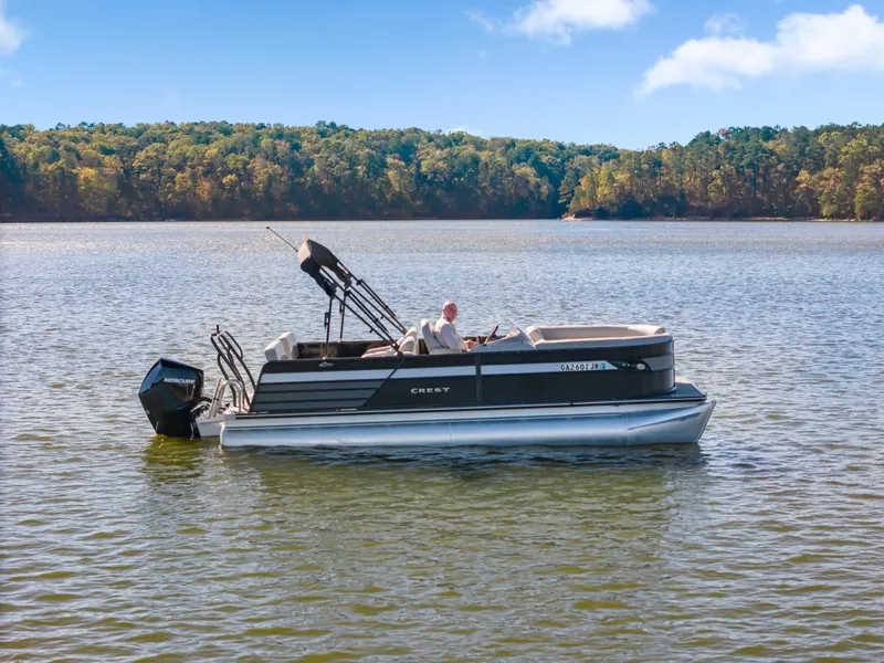 Slide: The Image of 2021 Crest Classic DLX 220 SLRC pontoon boat on a serene lake. - 1