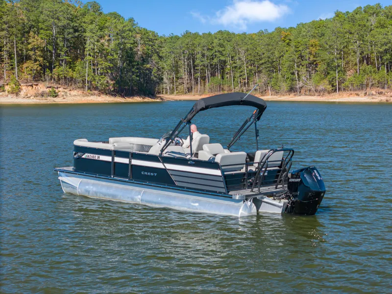 Slide: The Image of 2021 Crest Classic DLX 220 SLRC pontoon boat on a serene lake. - 3
