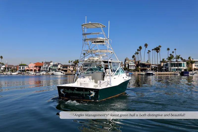 Slide: The Image of 2000 Cabo 35 Express boat with forest green hull cruising near waterfront homes. - 29
