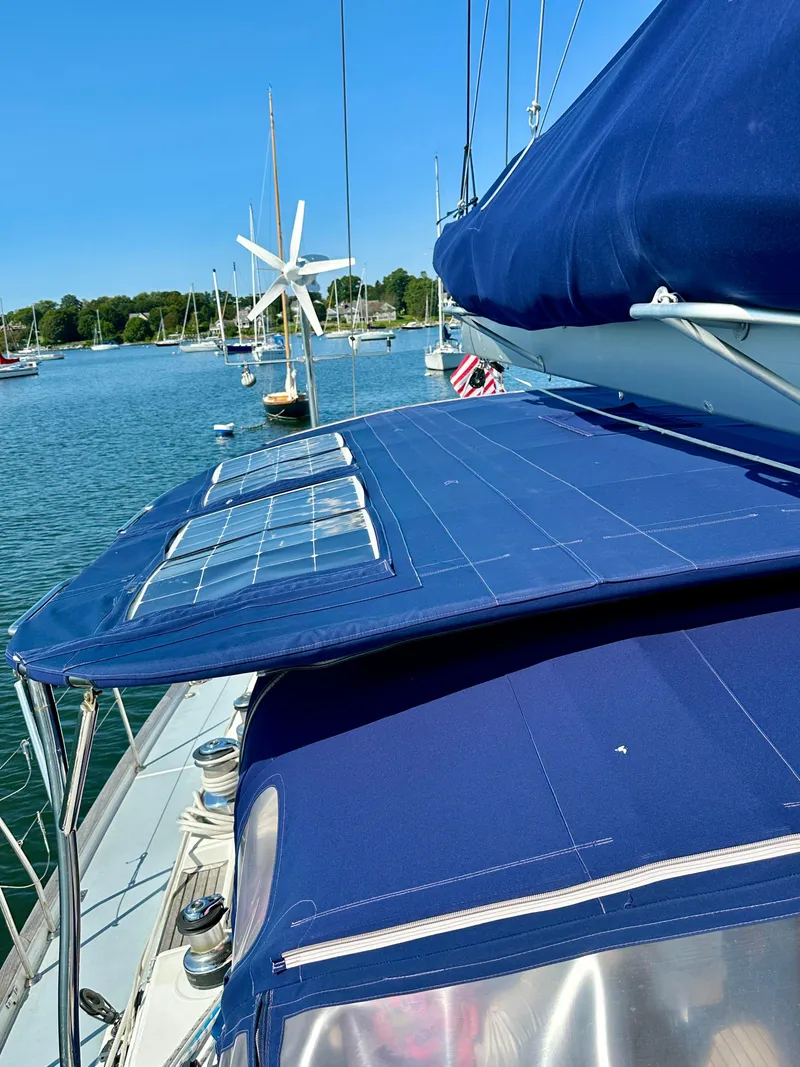 Slide: The Image of Beneteau 57 sailboat, 2010 model, with solar panels and wind turbine, docked in a serene marina. - 19