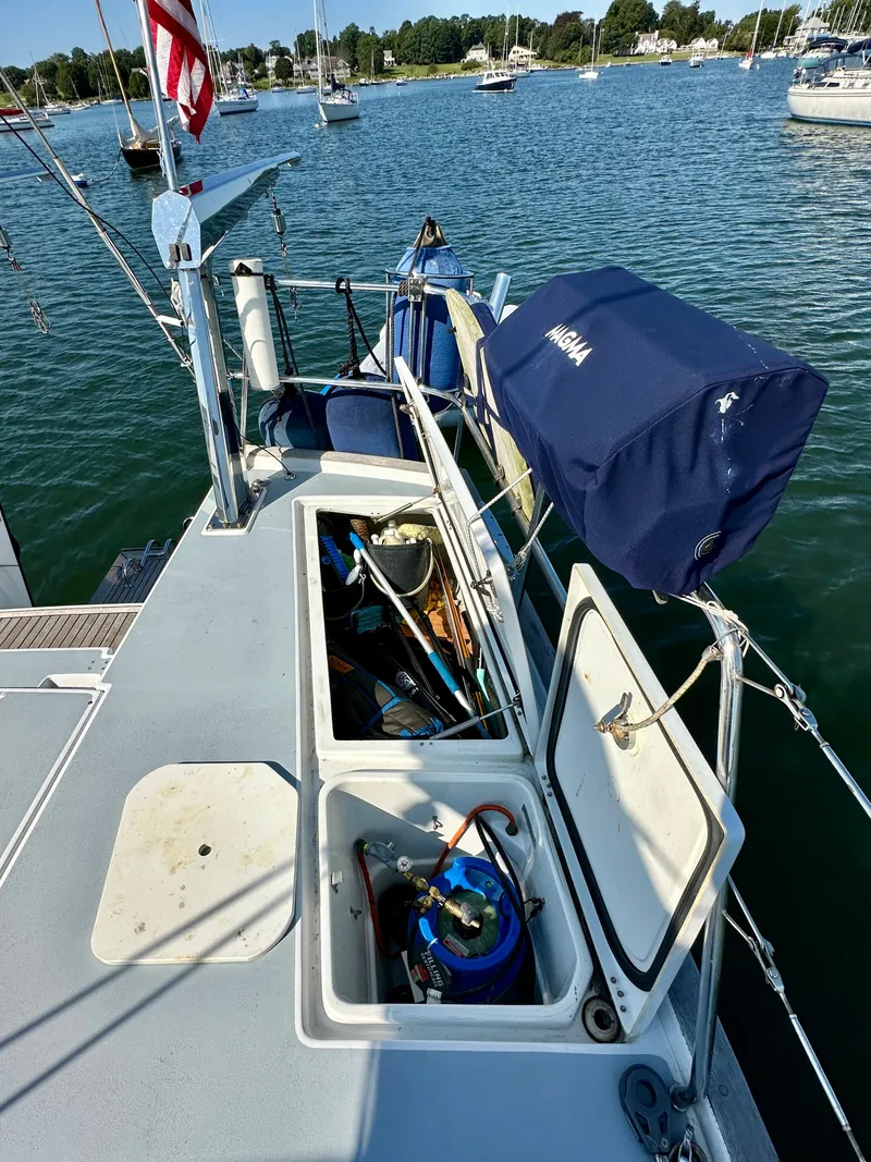 Slide: The Image of Beneteau 57 sailboat deck with open storage compartments, docked in a serene marina. - 21