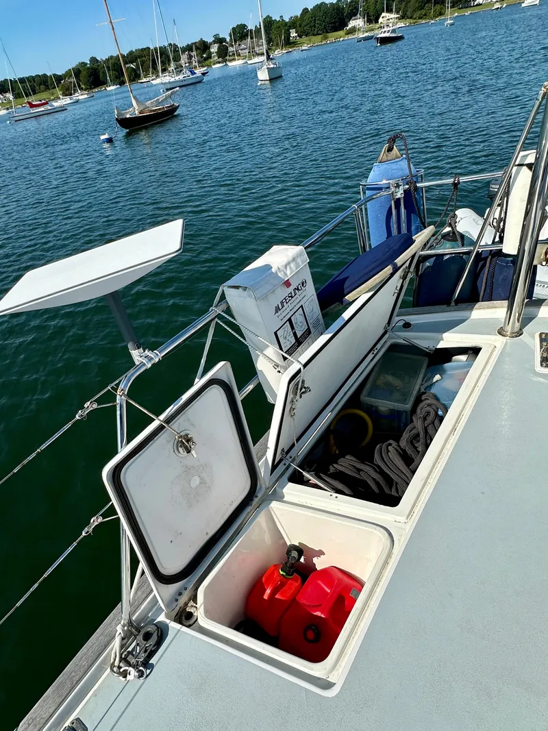 Slide: The Image of Beneteau 57 sailboat deck with open storage compartments, docked in a scenic marina. - 22