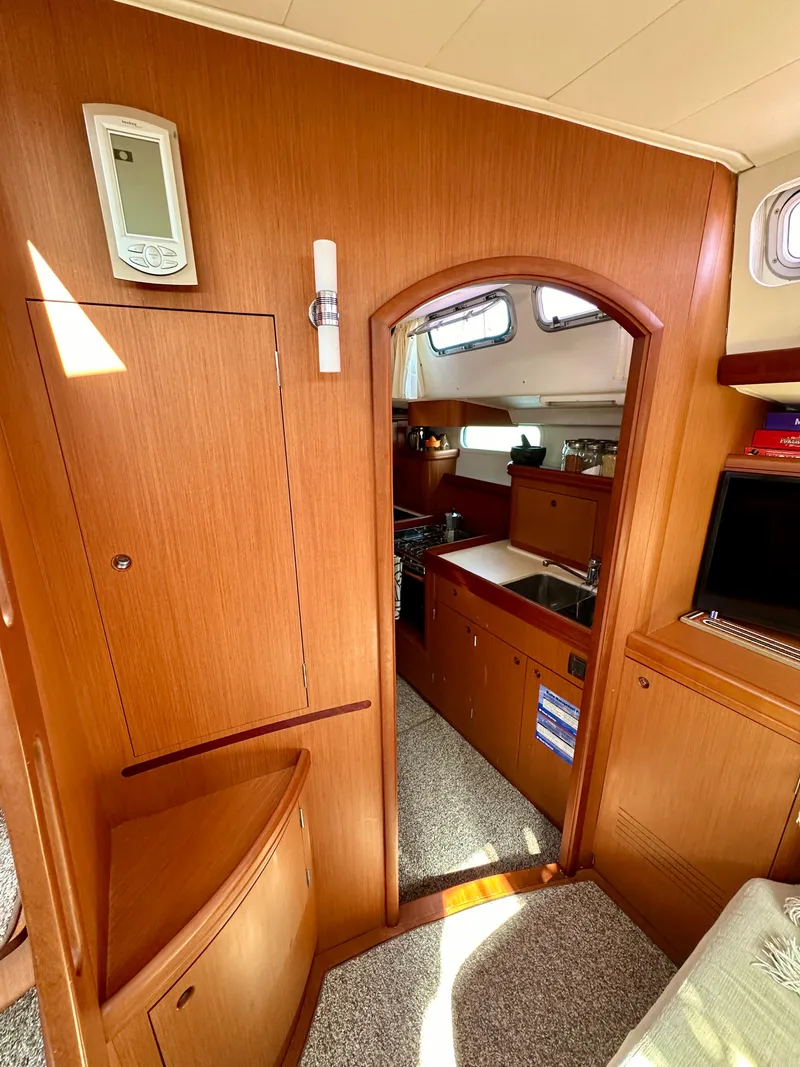 Slide: The Image of Interior of 2010 Beneteau 57 yacht, featuring wooden cabinetry and compact kitchen area. - 38