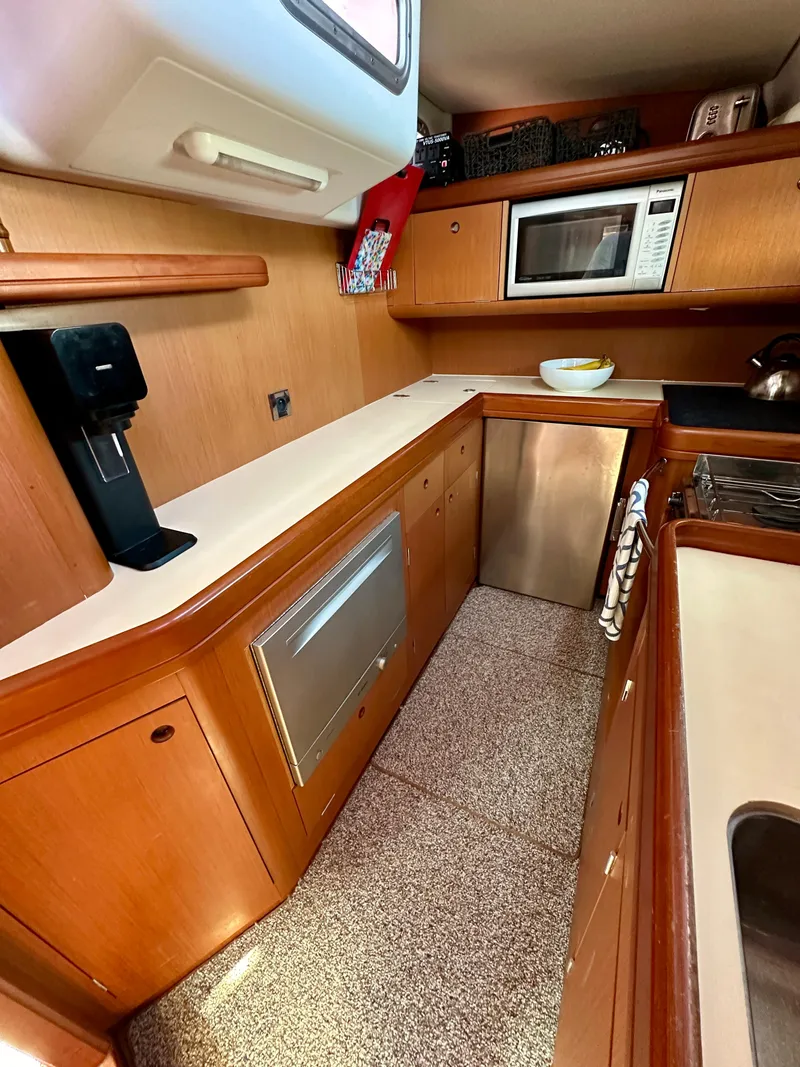 Slide: The Image of 2010 Beneteau 57 yacht kitchen with modern appliances and wooden cabinetry. - 40
