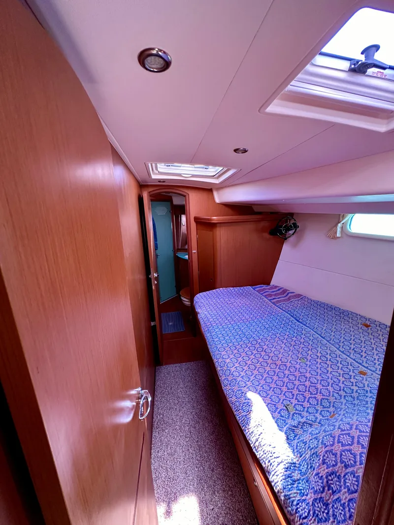 Slide: The Image of 2010 Beneteau 57 yacht cabin with cozy bed, wooden interior, and natural light. - 47