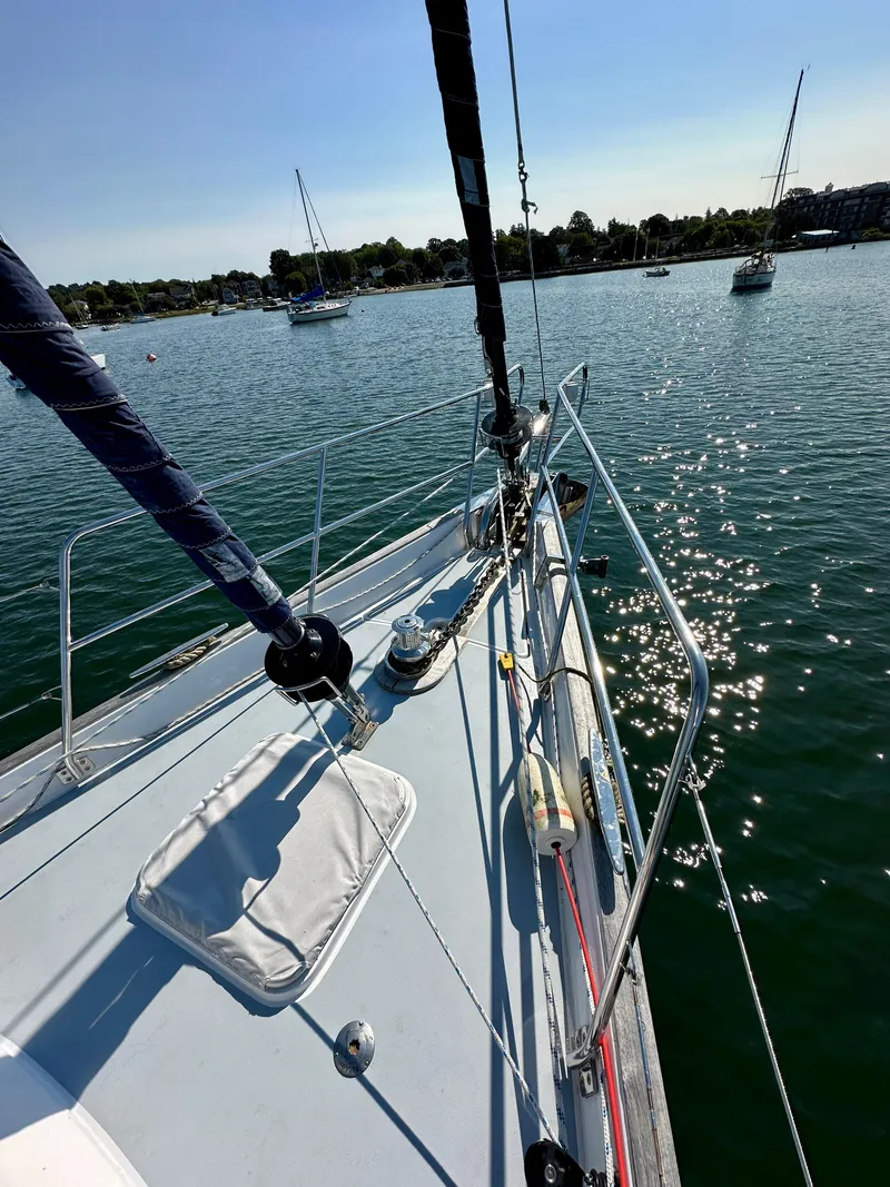 Slide: The Image of Sailing on a 2010 Beneteau 57 yacht, glistening water, clear sky, anchored boats in the distance. - 7