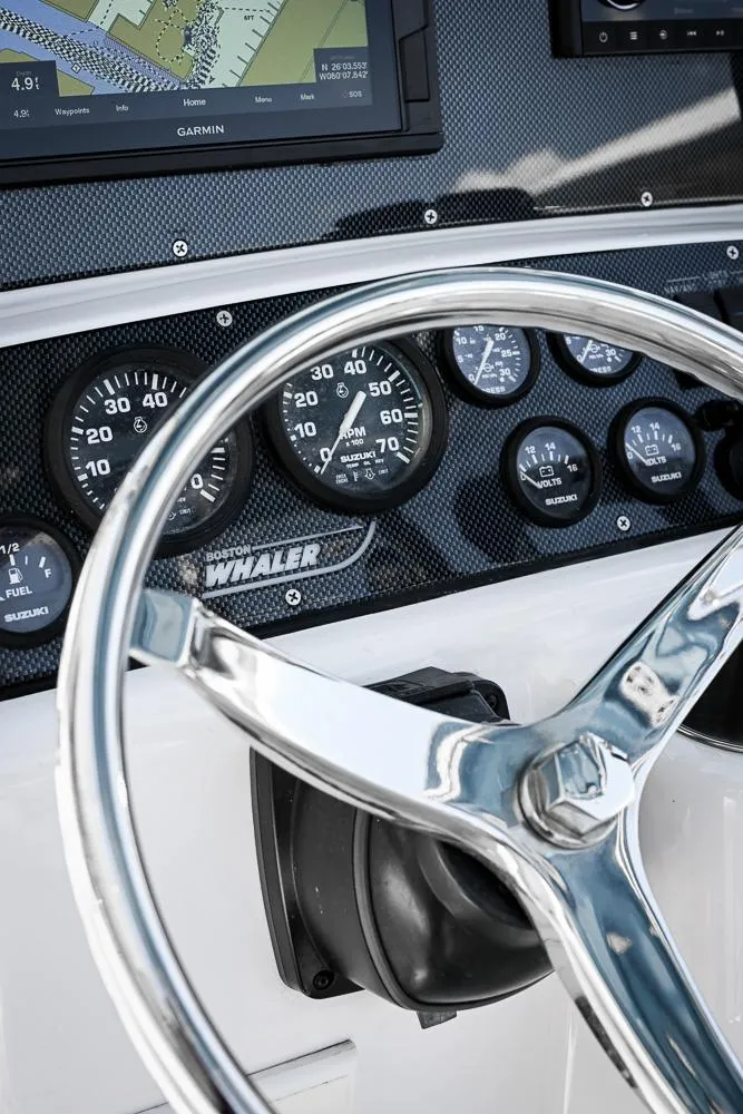 Slide: The Image of Steering wheel and dashboard of a 1999 Boston Whaler 26 boat with gauges and navigation display. - 5