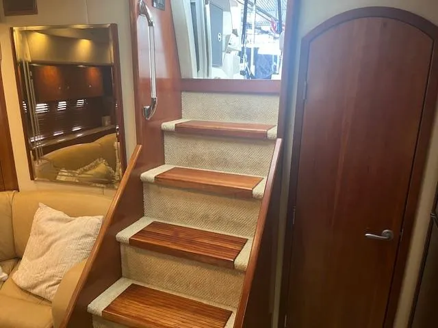 Slide: The Image of Interior of 2008 Cruisers Yachts 460 Express, featuring wooden stairs and cozy seating area. - 15